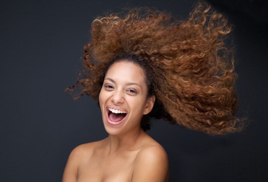 Close up portrait of an attractive young woman laughing with hair blowing